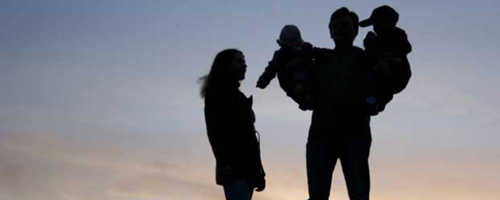 family with children on hands, sunset sky